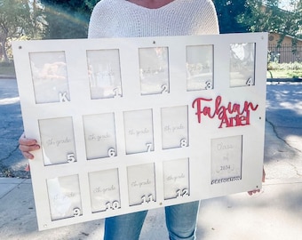 May include: White wooden picture frame with 12 individual frames for photos. Each frame is labeled with a grade level from kindergarten to 12th grade. The frame also includes the name "Fabian Ariel" and the text "Class of 2034 Graduation".