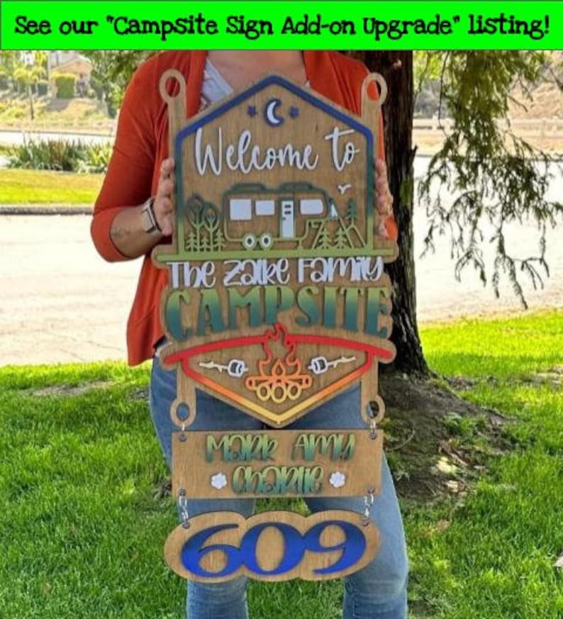 May include: Wooden campsite sign with a welcome to the Zalke family campsite message, a camper silhouette, a campfire, and a personalized nameplate with the names Mark, Amy, and Charlie and the number 609.