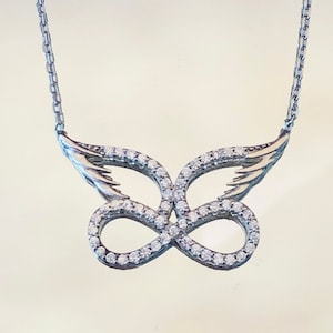 May include: A silver necklace with a butterfly pendant. The butterfly is made of silver and has a clear crystal design. The necklace is on a silver chain.