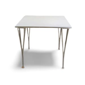 May include: A white rectangular table with a chrome-colored metal frame. The table has a smooth, white surface and four curved legs. The legs are made of shiny metal and are slightly splayed. The table is a modern design.