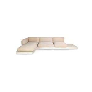 May include: A beige corner sofa with a chaise longue on the left. The sofa has a low profile and a minimalist design. The cushions are soft and inviting. The sofa sits on a white base. The sofa's dimensions are in centimetres.