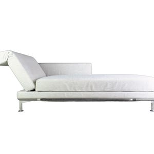 Op de afbeelding: Een witte chaise longue met een neerklappbare rugleuning en zilveren poten.
