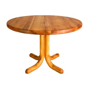 May include: A round wooden dining table with a light brown finish. The table has a pedestal base with four curved legs. The tabletop is made of wooden planks. The table is approximately 122 cm in diameter.
