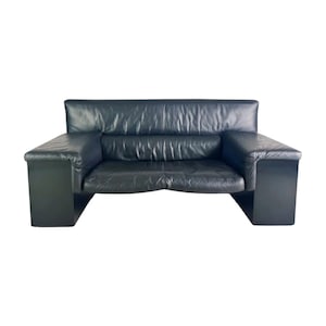 May include: A black leather sofa with a low profile and a modern design. The sofa has a two-cushion seat, a high back, and wide, rectangular armrests. The sofa is set against a white background.