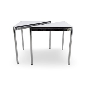 May include: Two triangular side tables featuring white tabletops with black edges and polished chrome metal frames. Each table is supported by three slender, cylindrical chrome legs, creating a clean, geometric design with a reflective finish.