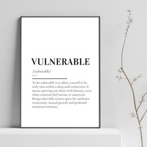 May include: A framed print with the word "VULNERABLE" in a bold, black font. Below the word is the phonetic pronunciation and a definition. The definition describes the essence of vulnerability and its role in fostering deep connections and emotional intimacy.