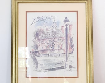 May include: Framed watercolor print of a historic building with a street scene. The artwork features a gold frame, a cream-colored mat, and a detailed depiction of a building with a cupola, a lamppost, and a horse-drawn carriage.