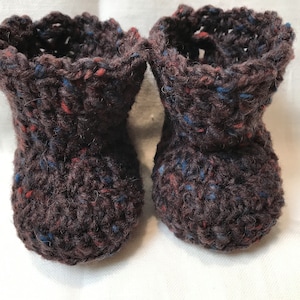 May include: A pair of brown crocheted baby booties with blue and red flecks in the yarn.