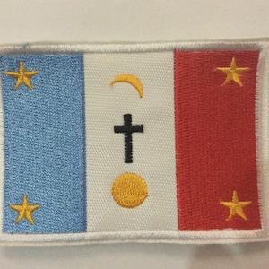 Puede incluir: Parche bordado con diseño de bandera. Tiene rayas verticales azules, blancas y rojas. La franja blanca tiene una cruz negra, una media luna amarilla y un círculo amarillo. Estrellas amarillas están en las rayas azules y rojas.