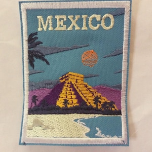 Puede incluir: Parche bordado con una escena mexicana. Muestra una pirámide amarilla, palmeras, una playa y un sol poniente sobre un cielo azul. La palabra "MEXICO" está bordada en la parte superior del parche.