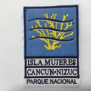 May include: Embroidered patch featuring a blue background with a yellow coral design and three horizontal blue lines. The text "ISLA MUJERES CANCUN-NIZUC PARQUE NACIONAL" is displayed in white letters.