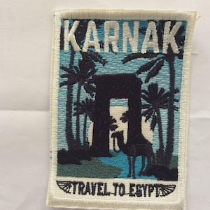 May include: Embroidered patch with the word KARNAK in white above a scene of palm trees, a camel, and an archway. The text "TRAVEL TO EGYPT" is at the bottom. The background is light blue with a white border.