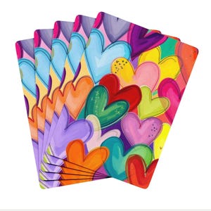 May include: A stack of cards with a colourful heart design. The cards display a vibrant pattern of overlapping hearts in shades of blue, orange, green, red, pink, and yellow. The hearts are outlined in black and have a painted appearance.