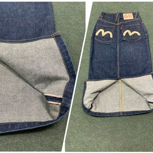 Pu&ograve; includere: Una gonna in denim blu scuro con un logo bianco sulle tasche posteriori. La gonna ha uno spacco sul retro e una fodera bianca.