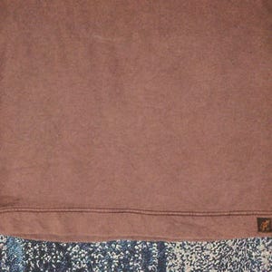 Pode incluir: Uma camisa marrom de manga comprida e gola redonda. A camisa tem uma apar&ecirc;ncia texturizada e um pequeno patch com o logotipo perto da bainha. As mangas s&atilde;o de um tom marrom ligeiramente mais claro do que o corpo.