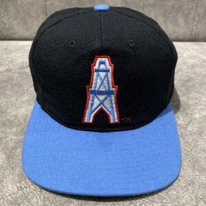 May include: Black baseball cap with a light blue brim and top button. The cap features an embroidered logo of a white and light blue oil derrick with a red outline. The cap has a structured fit.