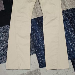 May include: Light beige trousers with a straight leg cut. The fabric appears smooth, and the colour is a neutral beige. These trousers are suitable for casual or semi-formal occasions.