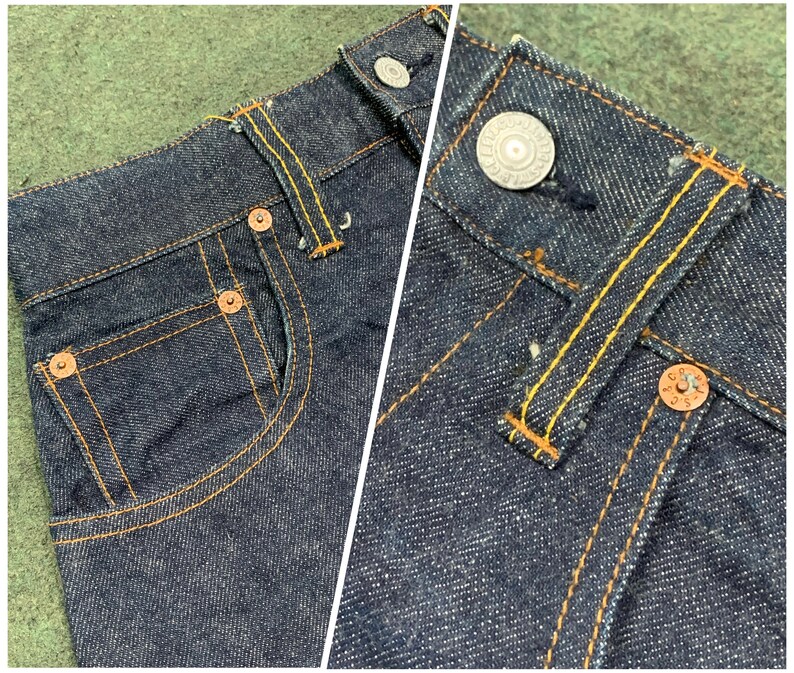 Pu&ograve; includere: Primo piano di jeans in denim blu scuro con rivetti in rame e cuciture gialle. I jeans hanno uno stile classico a cinque tasche con un dettaglio di tasca posteriore.