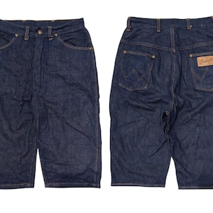 May include: Dark wash denim shorts with a classic five-pocket design. The shorts feature a button and zipper closure, belt loops, and the Wrangler brand patch on the back. The shorts are shown from the front and back.