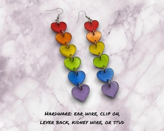 May include: Rainbow heart dangle earrings with glitter. The earrings are available in ear wire, clip on, lever back, kidney wire, or stud hardware.
