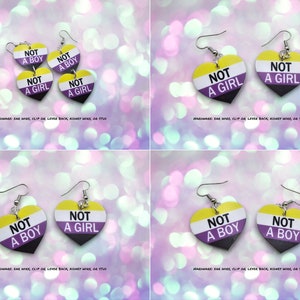 May include: A set of four heart-shaped earrings with the words "Not a Boy" and "Not a Girl" printed on them. The earrings are painted in the colors of the non-binary pride flag: yellow, white, and purple.