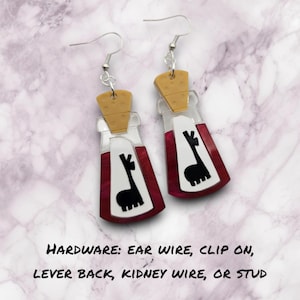 May include: A pair of earrings featuring a red and white bottle with a llama silhouette. The bottle has a gold top and the earrings are available in ear wire, clip on, lever back, kidney wire, or stud hardware.
