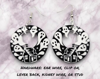 May include: Black and white round earrings with a design of a house and ghosts. The text "HARDWARE: EAR WIRE, CLIP ON, LEVER BACK, KIDNEY WIRE, OR STUD" is below the earrings.