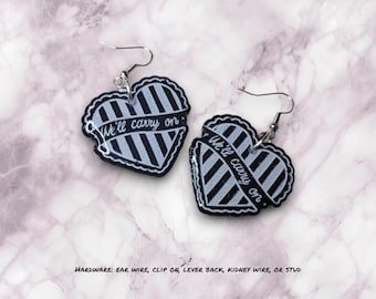 May include: A pair of black and white striped heart-shaped earrings with the text "We'll carry on" on each earring.