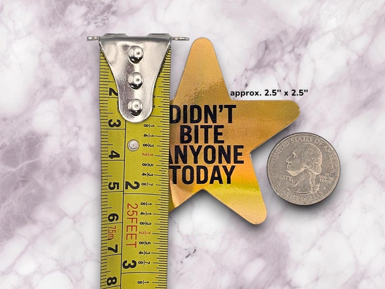 May include: Gold star-shaped sticker with the text "Didn't Bite Anyone Today" in black lettering. The sticker measures approximately 2.5 inches by 2.5 inches.