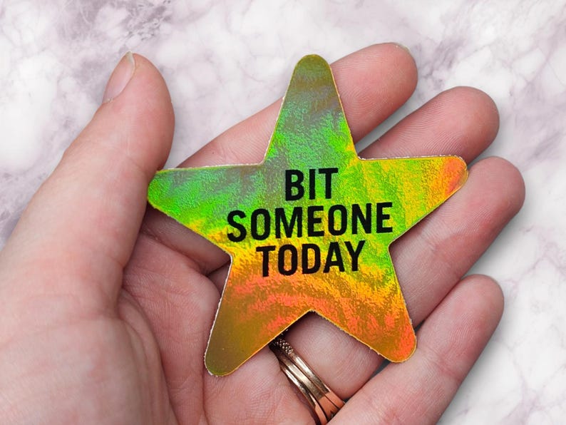 May include: A holographic star-shaped sticker with the text "Bit Someone Today" in black lettering.
