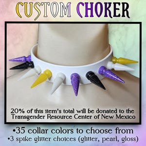 Könnte beinhalten: Ein weißes Choker-Halsband mit bunten Stacheln. Die Stacheln sind in verschiedenen Farben, darunter Lila, Schwarz, Gelb und Weiß. Der Text "CUSTOM CHOKER" steht oben. Der Text besagt auch, dass 20 % des Gesamtbetrags des Artikels an das Transgender Resource Center of New Mexico gespendet werden.