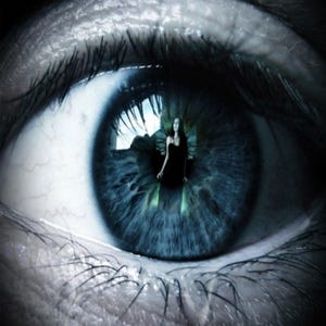 Op de afbeelding: Een close-up van een menselijk oog met een blauwe iris, waarin een persoon in een zwarte jurk in de pupil wordt weerspiegeld. De tekst "REMOTE" staat bovenaan en "VIEWING" onderaan in een strak, wit schreefloos lettertype op een donkere achtergrond.
