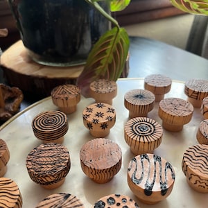 K&ouml;nnte beinhalten: Eine Sammlung von 15 Holzgriffen mit verschiedenen geometrischen Mustern in Schwarz und Wei&szlig;. Die Griffe sind rund und haben eine nat&uuml;rliche Holzoptik.