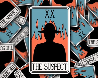 May include: A tarot card with a blue background and orange flames. The card depicts a person wearing a black hat and a black suit. The text on the card reads "XX THE SUSPECT".