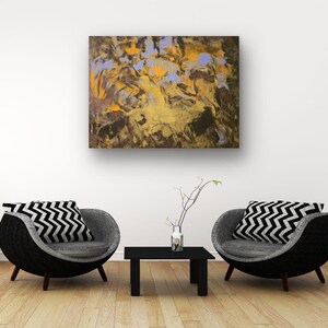 Puede incluir: Lienzo de arte abstracto con tonos dorados, marrones y azules. Dos cojines con estampado de zigzag en blanco y negro descansan sobre sillas grises. Una peque&ntilde;a mesa negra y un jarr&oacute;n con ramas completan la escena.