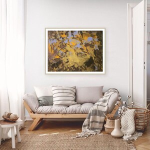 Puede incluir: Impresi&oacute;n art&iacute;stica abstracta en un marco dorado. La obra presenta una mezcla de tonos amarillos, marrones y azules. La pintura cuelga sobre un sof&aacute; de madera con cojines y una manta a rayas. Una alfombra tejida y cestas completan el interior.