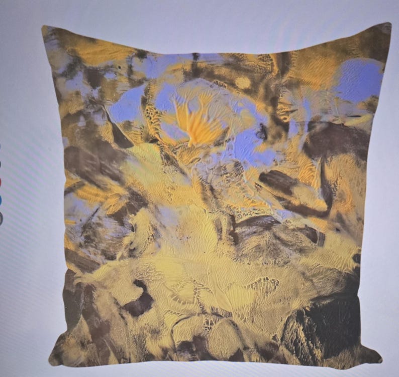 Puede incluir: Coj&iacute;n cuadrado con un dise&ntilde;o abstracto. El coj&iacute;n presenta una mezcla de colores, incluyendo amarillo, azul y marr&oacute;n, creando una apariencia texturizada y art&iacute;stica. El dise&ntilde;o se asemeja a un paisaje o una pintura de acuarela.