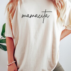 May include: A white oversized t-shirt with the text "mamacita" in black script.