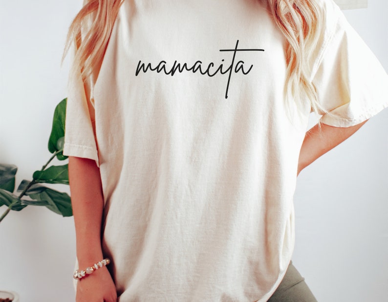 May include: A white oversized t-shirt with the text "mamacita" in black script.