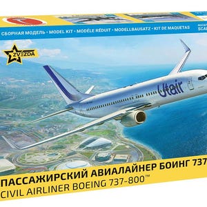 Puede incluir: Una caja de kit de modelismo Zvezda a escala 1/144 de un avión comercial Boeing 737-800. La caja presenta una ilustración de un avión de pasajeros UTair blanco y azul en vuelo sobre un paisaje costero, con el texto Civil Airliner Boeing 737-800.