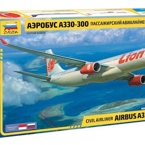 May include: A model kit box for an Airbus A330-300 passenger airliner. The box art depicts the aircraft in flight over a blue ocean. The plane is white with red engine cowlings and the text "Lion" on the fuselage. The box also includes the text "Civil Airliner Airbus A330-300".
