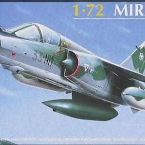 May include: A 1/72 scale model kit of a Mirage F1 CR fighter jet. The model is painted in a camouflage pattern of green, brown, and grey. The kit is made by Heller.