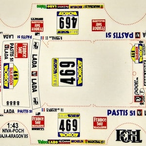 Può includere: Un foglio di decalcomanie bianco con vari adesivi per un'auto da rally Lada Niva. Gli adesivi includono il numero della vettura "469", il marchio "MONROE", lo sponsor "PASTIS 51" e la gara "BAJA-ARAGON 85".