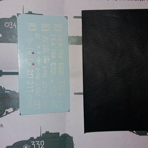 Puede incluir: Una hoja de calcomanías blancas con números y símbolos negros. Las calcomanías son para un tanque modelo. Los números incluyen 154, 158, 522, 332, 217, 217, 0345, 3-700, 341, 3410, 3-700, 3450 y 755. Los símbolos incluyen una estrella, un triángulo y un círculo.