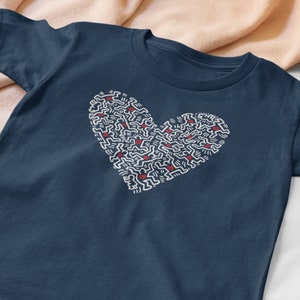 Pode incluir: Uma camiseta azul marinho com um design branco em forma de cora&ccedil;&atilde;o. O cora&ccedil;&atilde;o &eacute; feito de pequenas figuras repetidas.