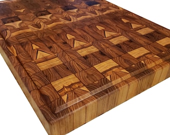 May include: A rectangular wooden cutting board with a mosaic pattern. The board is made of various shades of brown wood, creating a visually appealing design. It features a recessed edge and is suitable for kitchen use.