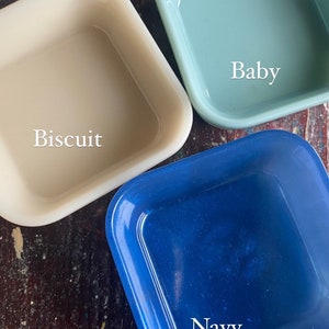 May include: Three square ceramic dishes in different colors: biscuit, baby blue, and navy blue. The dishes are labeled with their color names.
