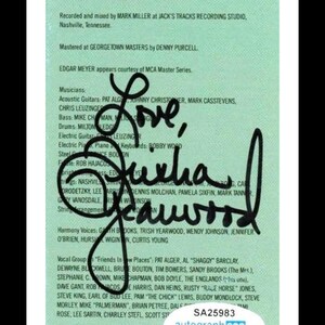 May include: A signed album insert with the words "Love, Sucha, Cawwood" in black ink. The insert lists the production credits, musicians, and vocal groups. A sticker at the bottom reads "SA25983 autograph coa ACOA AUTHENTICATED."