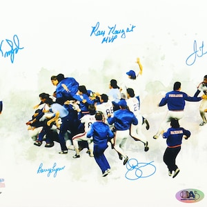 May include: A baseball team celebrating a victory, with players in blue and white uniforms. The image includes signatures and the words "World Series". A baseball is in the lower right corner.