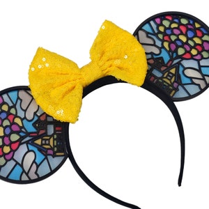 May include: Black headband with a yellow bow and two black ears. Each ear has a stained glass design of a house with balloons.